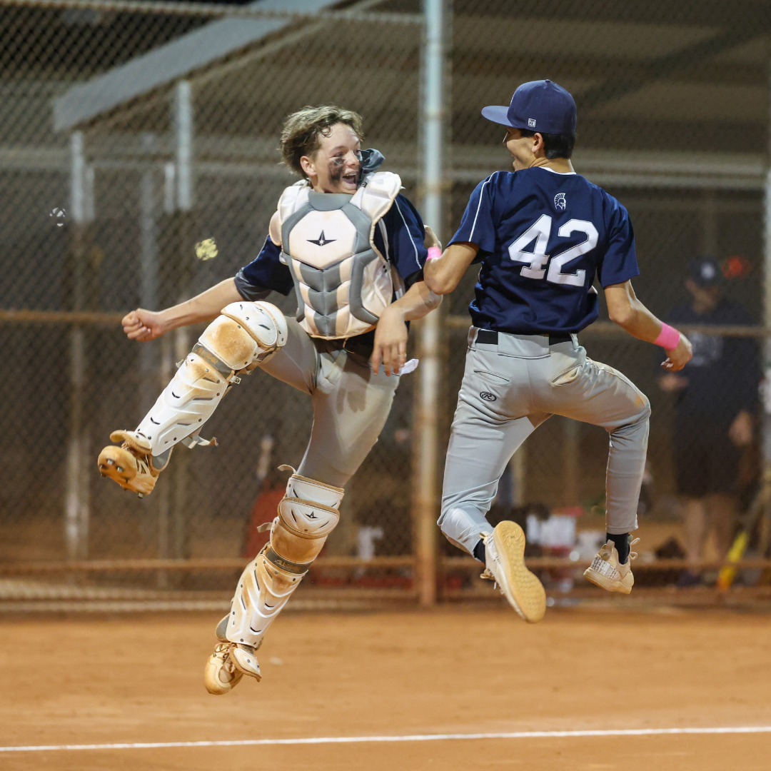 Two Middle School baseball players jumping in mid air