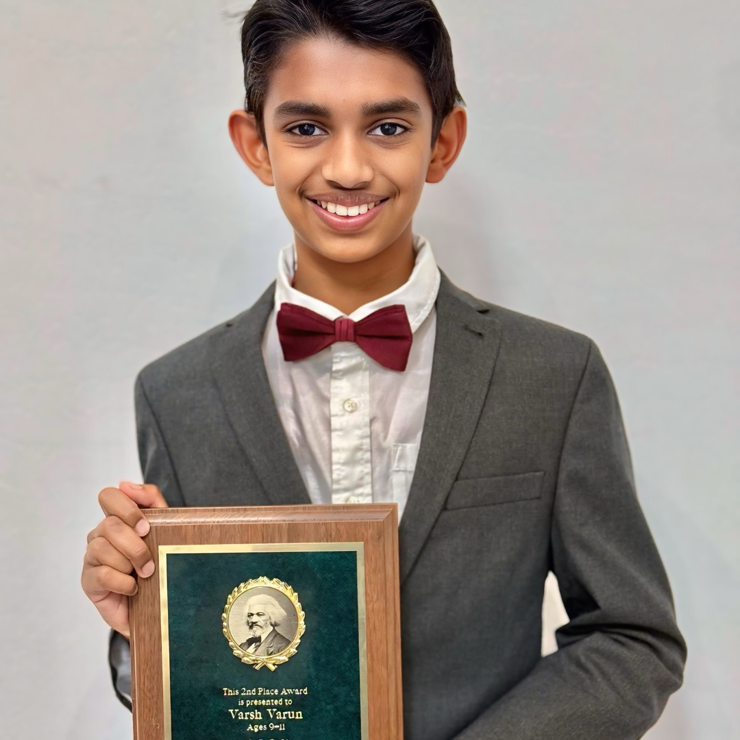 Student wearing suit and bow tie holding a 2nd place plaque