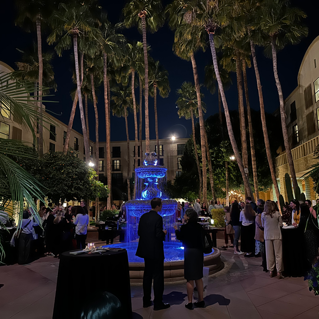 A courtyard with a fountain palm trees at night