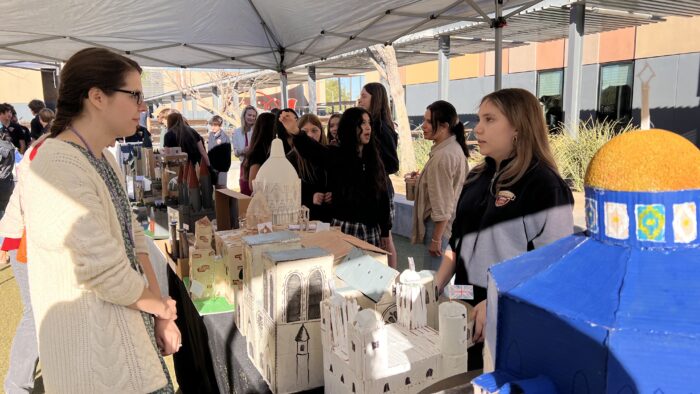 Student displaying her architectural project for a teacher.