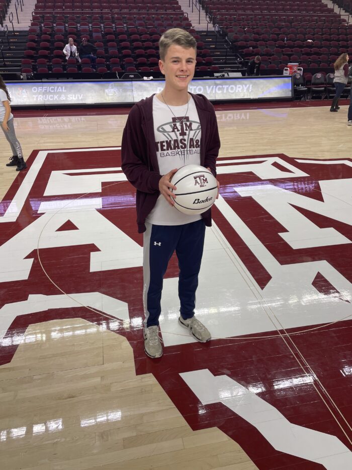 Student wearing Texas A&M gear on a basketball court