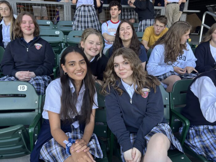 group of students sitting in the stands at a baseball field